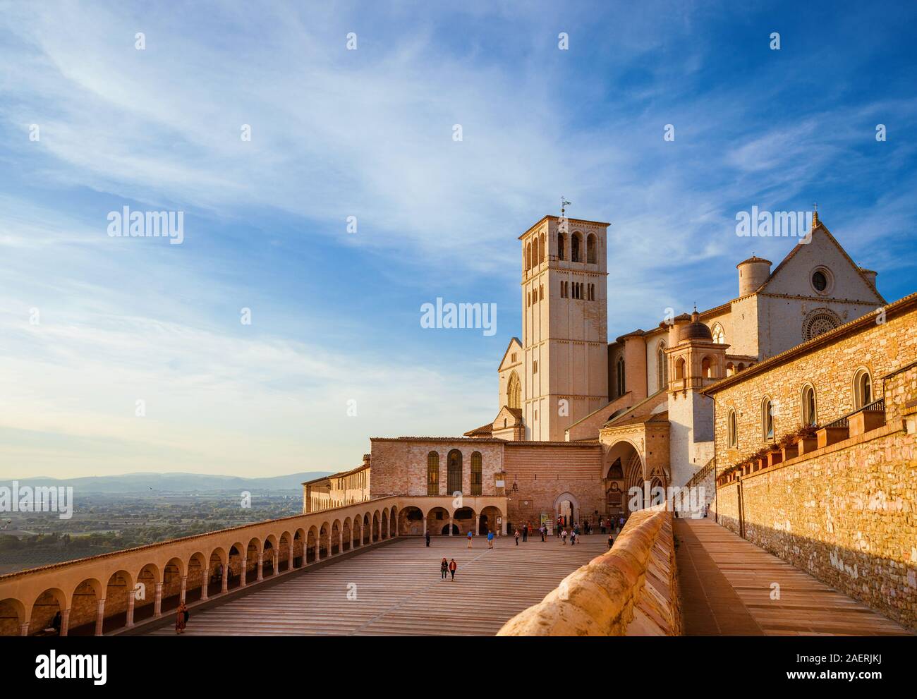 Touristen besuchen Sie die berühmte Basilika des Heiligen Franziskus von Assisi in Umbrien bei Sonnenuntergang Stockfoto