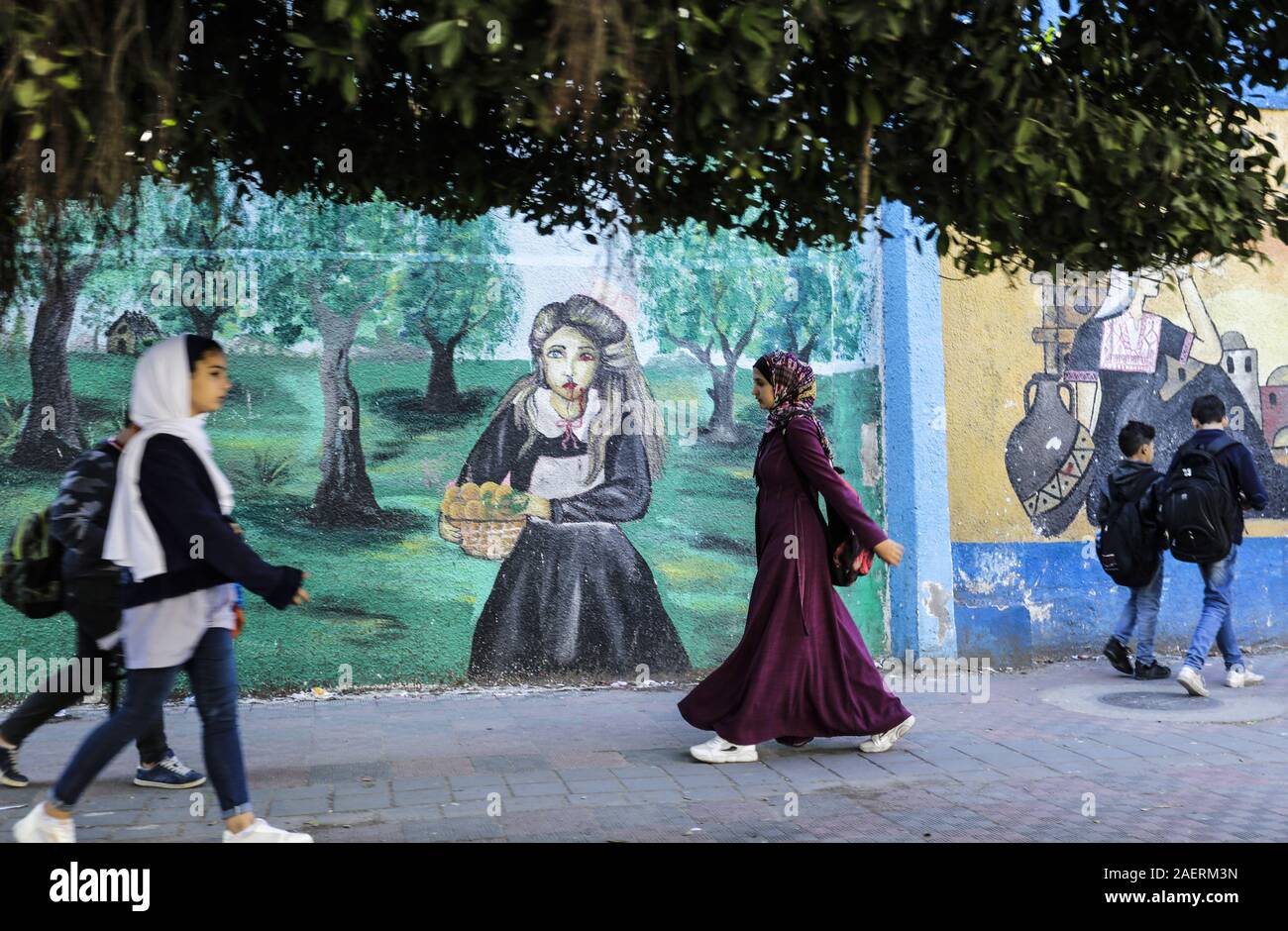 Gaza, Palästina. 3. Dezember, 2019. Die Palästinenser hinter einem Wandbild an der Wand der Vereinten Nationen für Flüchtlinge (UNRWA) in Gaza Stadt. Credit: Mahmoud Issa/SOPA Images/ZUMA Draht/Alamy leben Nachrichten Stockfoto