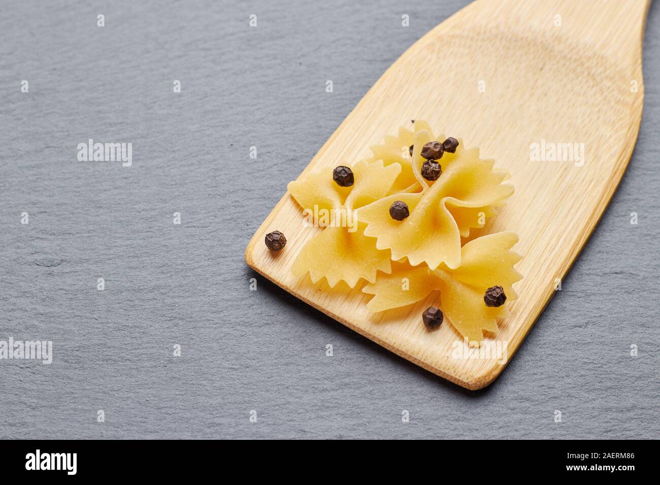 Pasta Schmetterling mit Pfeffer auf einem Holzspachtel entfernen. Stockfoto