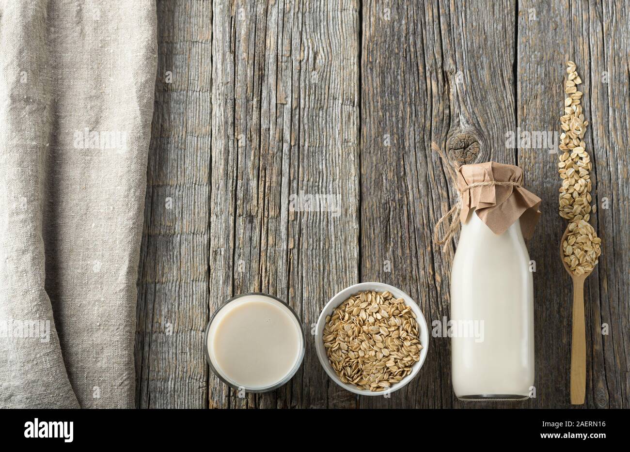 Hafermilch in eine Flasche und ein Glas auf einem Holztisch. Milch und Zutaten und flach. Ohne Milchprodukte Milch Produkt. Bild mit Kopie Raum, senkrecht. Stockfoto