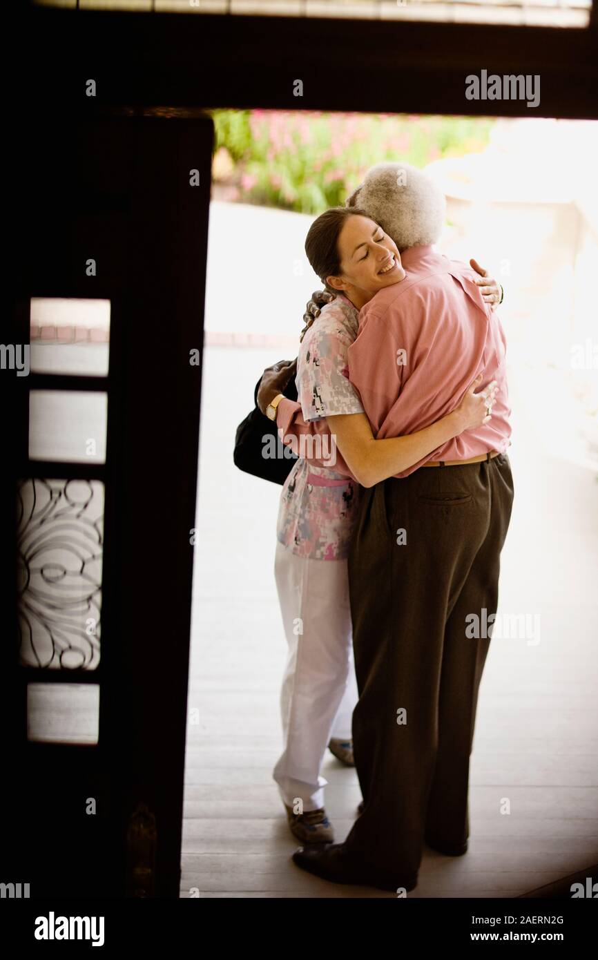 Junge Krankenschwester umarmt Sie ältere Patienten. Stockfoto