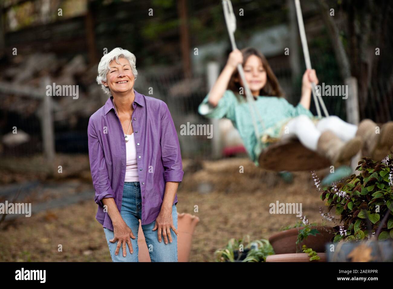 Ältere Frau schiebt ihre Enkelin auf einer Schaukel. Stockfoto