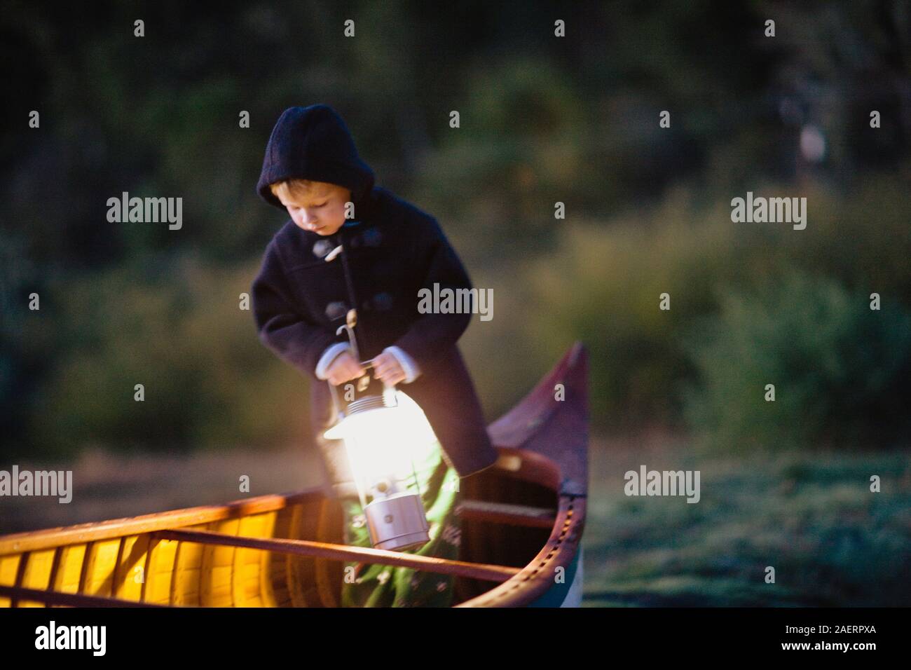 Junge steht in einem Kanu eine Laterne. Stockfoto