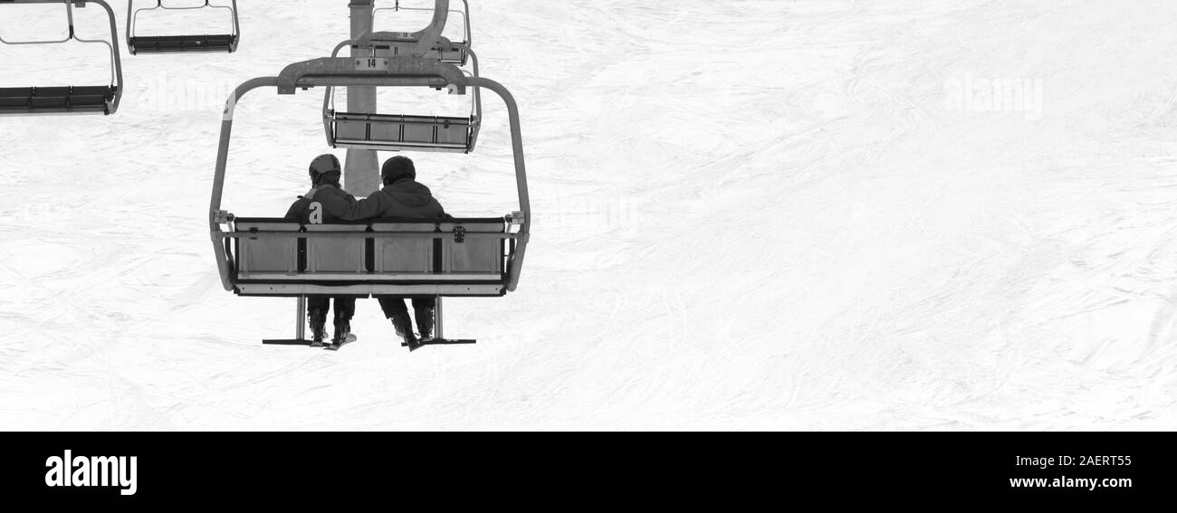 Zwei Skifahrer auf der Sesselbahn in grauer Tag. Verschneiten Kaukasus Berge im Winter. Hatsvali, Swaneti Region Georgiens. Schwarz und Weiß getönten Landschaft. Panora Stockfoto