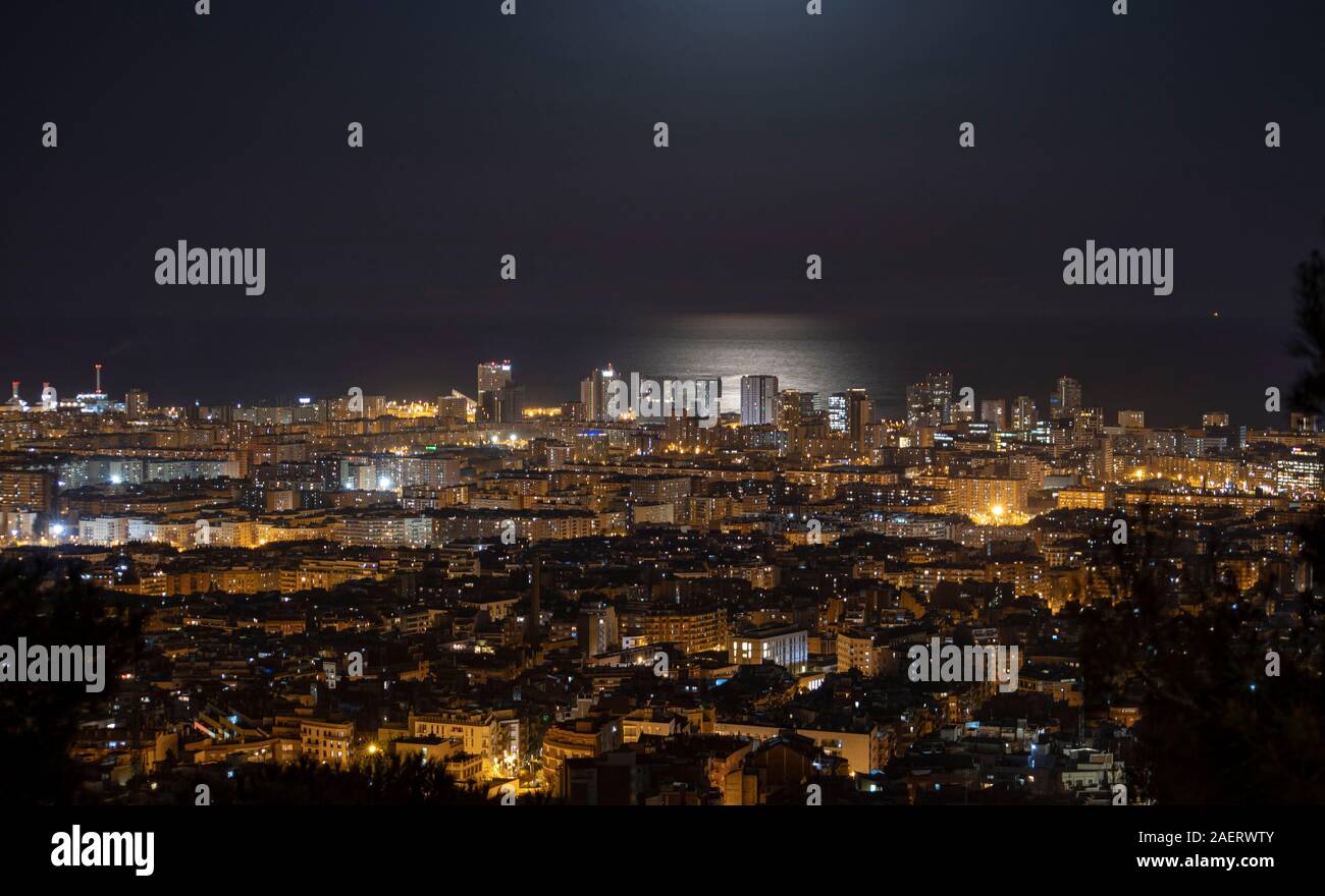 Barcelona Skyline bei Nacht mit dem Mond über dem Meer Stockfoto