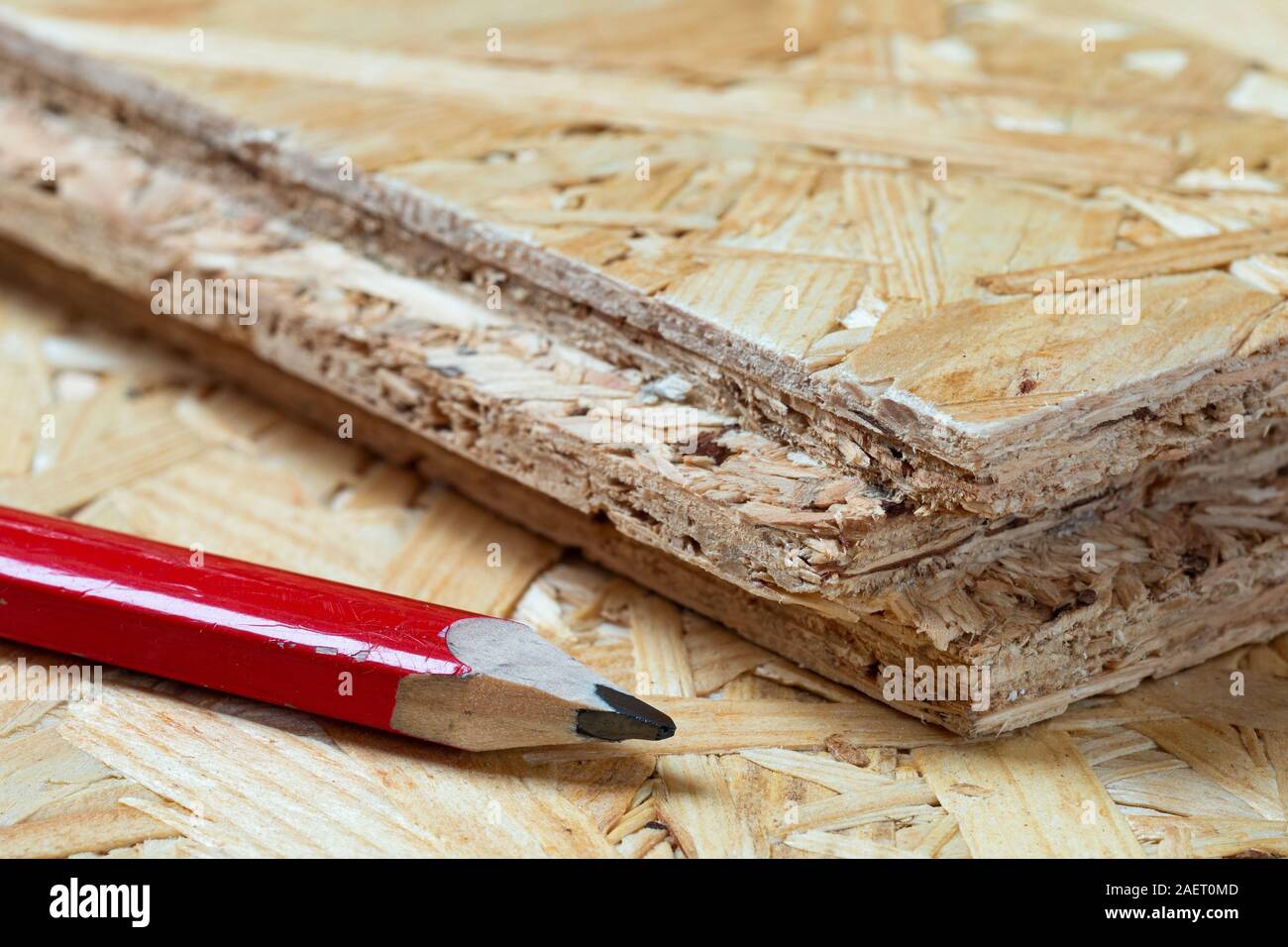 Red Zimmermanns Bleistift nebeneinander liegend Nut- und Spanplatten. Unscharfer Hintergrund. Stockfoto