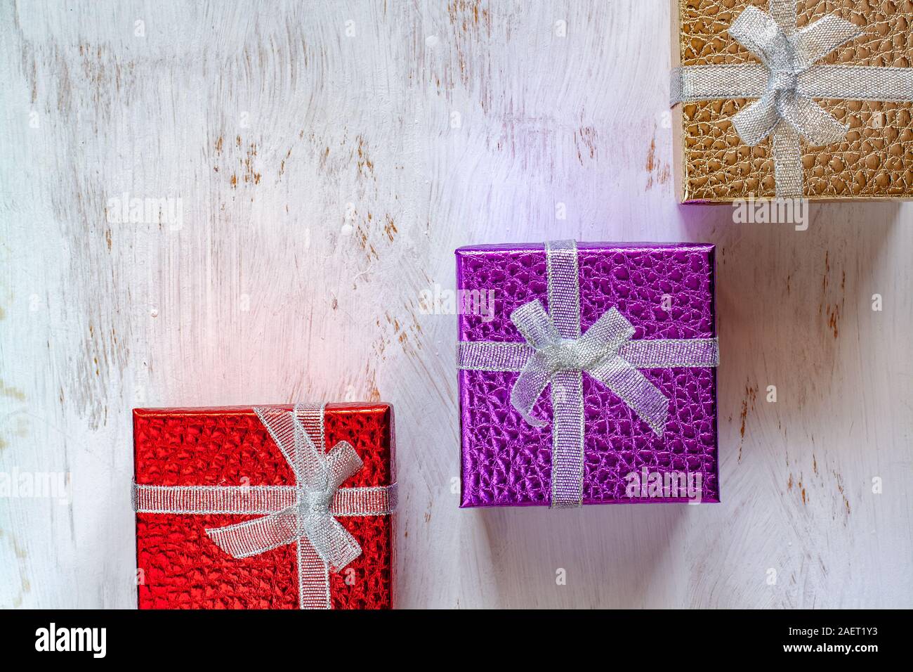 Flach. Drei Geschenkboxen mit Bogen auf einem weißen Untergrund mit Pinsel gemalt. Rot, Purpur und Gold Boxen. Kopieren Sie Platz. Stockfoto