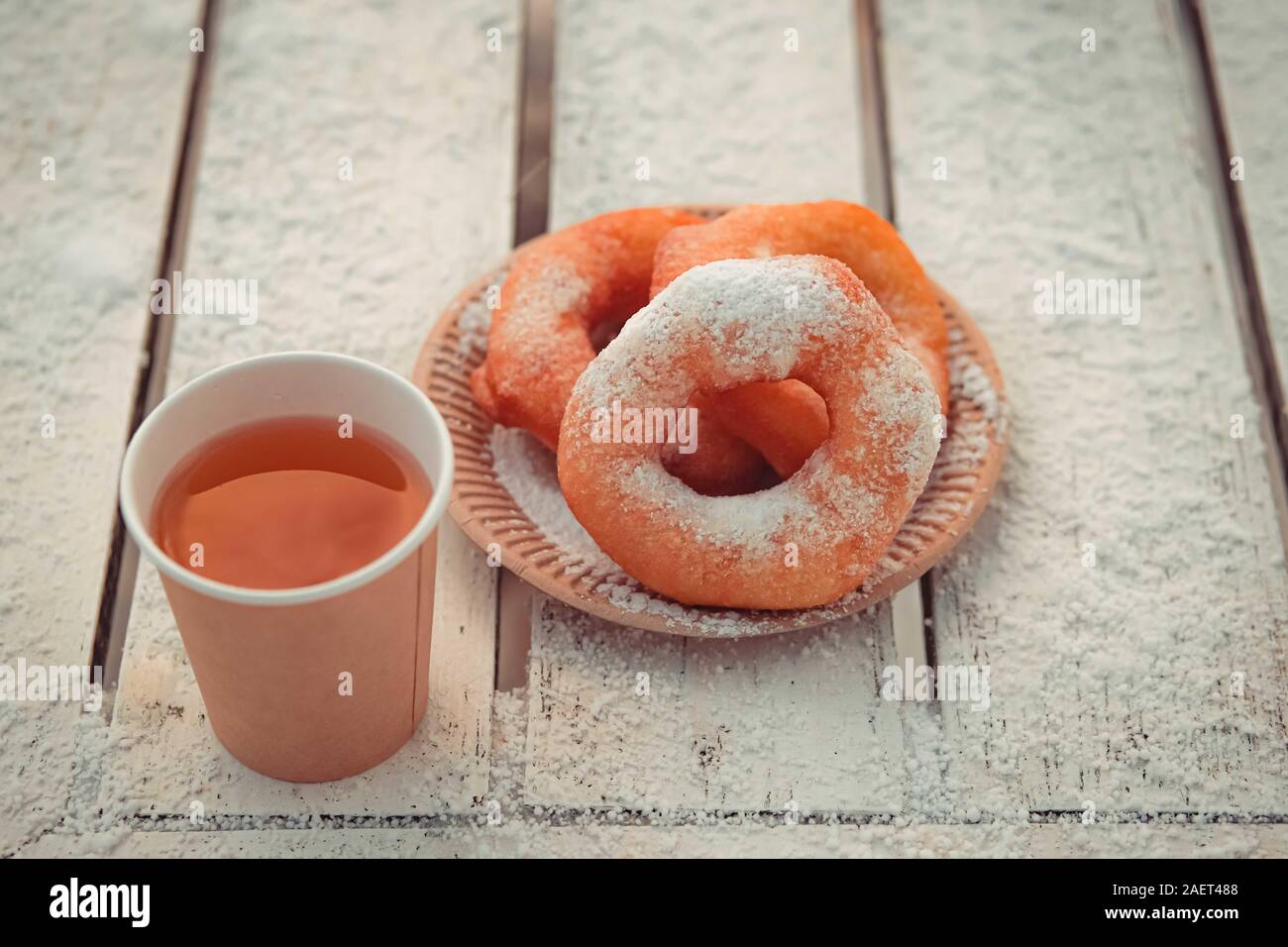 Russische fast food Bagel pyshki und Papier Tasse mit Tee oder Kaffee auf hölzernen Tisch, bedeckt mit Schnee, Winter Snack im Park. Stockfoto