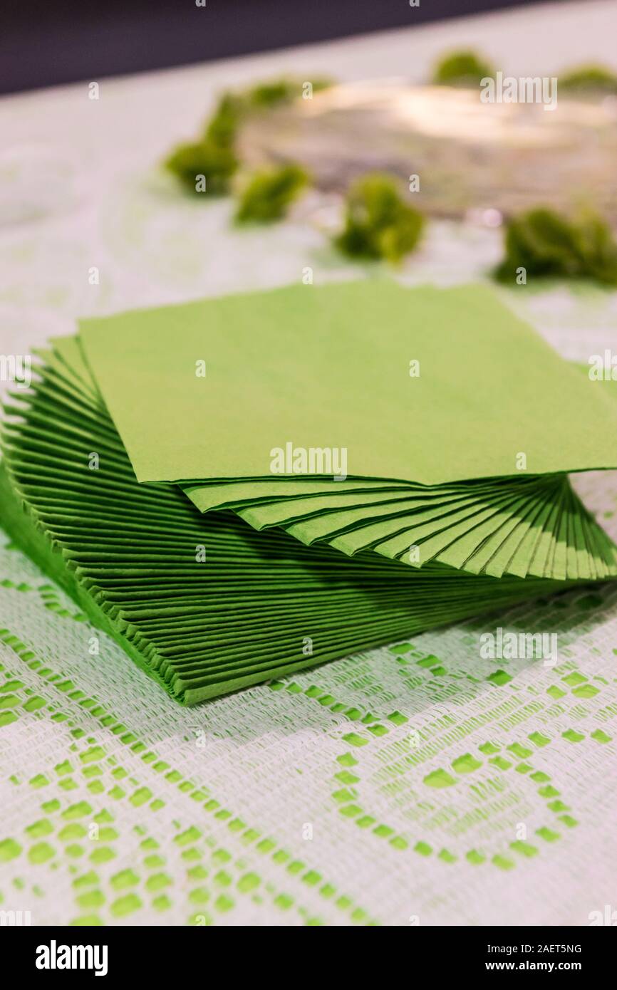 Einige grüne/Salbei farbige Servietten Torsion auf eine Tabelle mit Spitze Tischdecke angehäuft. Stockfoto