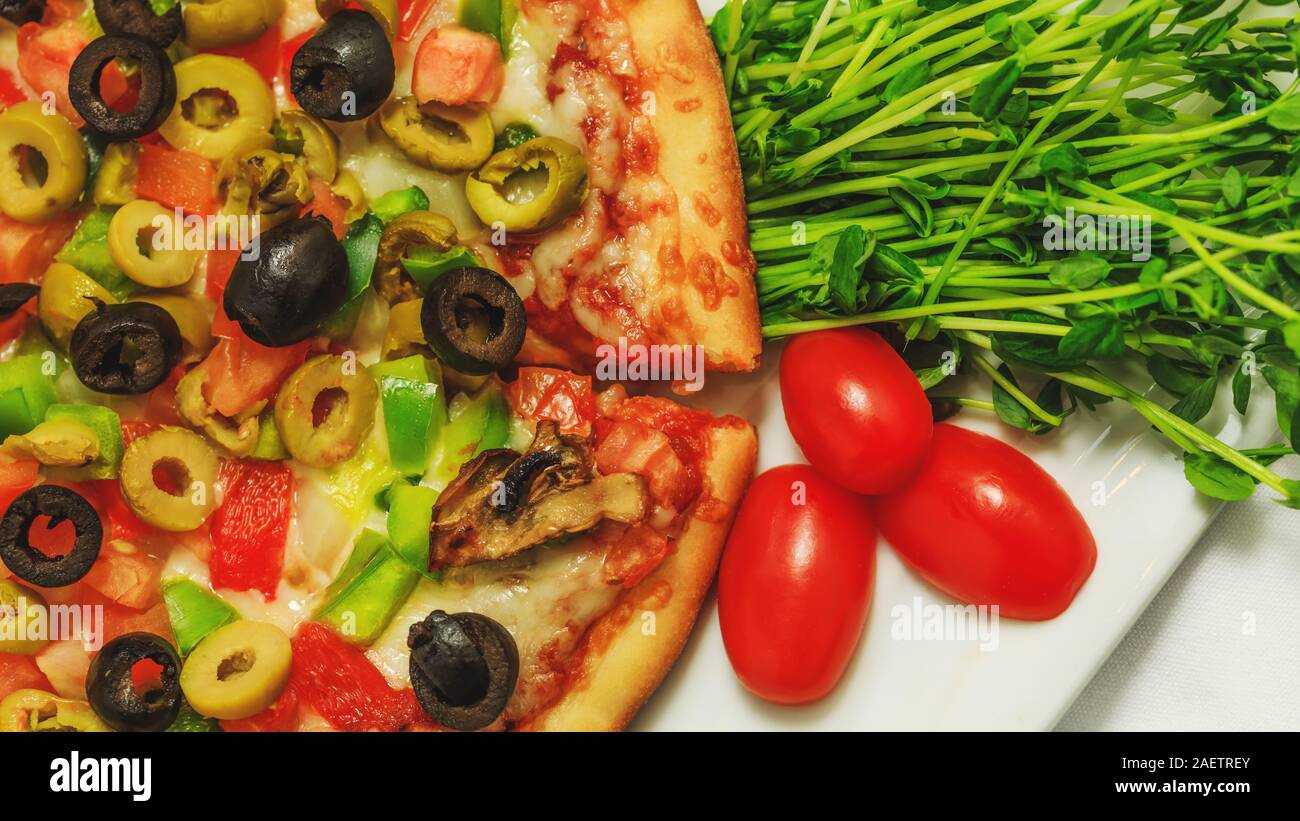 Pizza mit Oliven, Peperoni und rote Tomaten, traditionelle italienische Küche. Blick von oben auf die gebackenen Gemüse Pizza auf Tisch im Restaurant. In der Nähe von Romantik Stockfoto