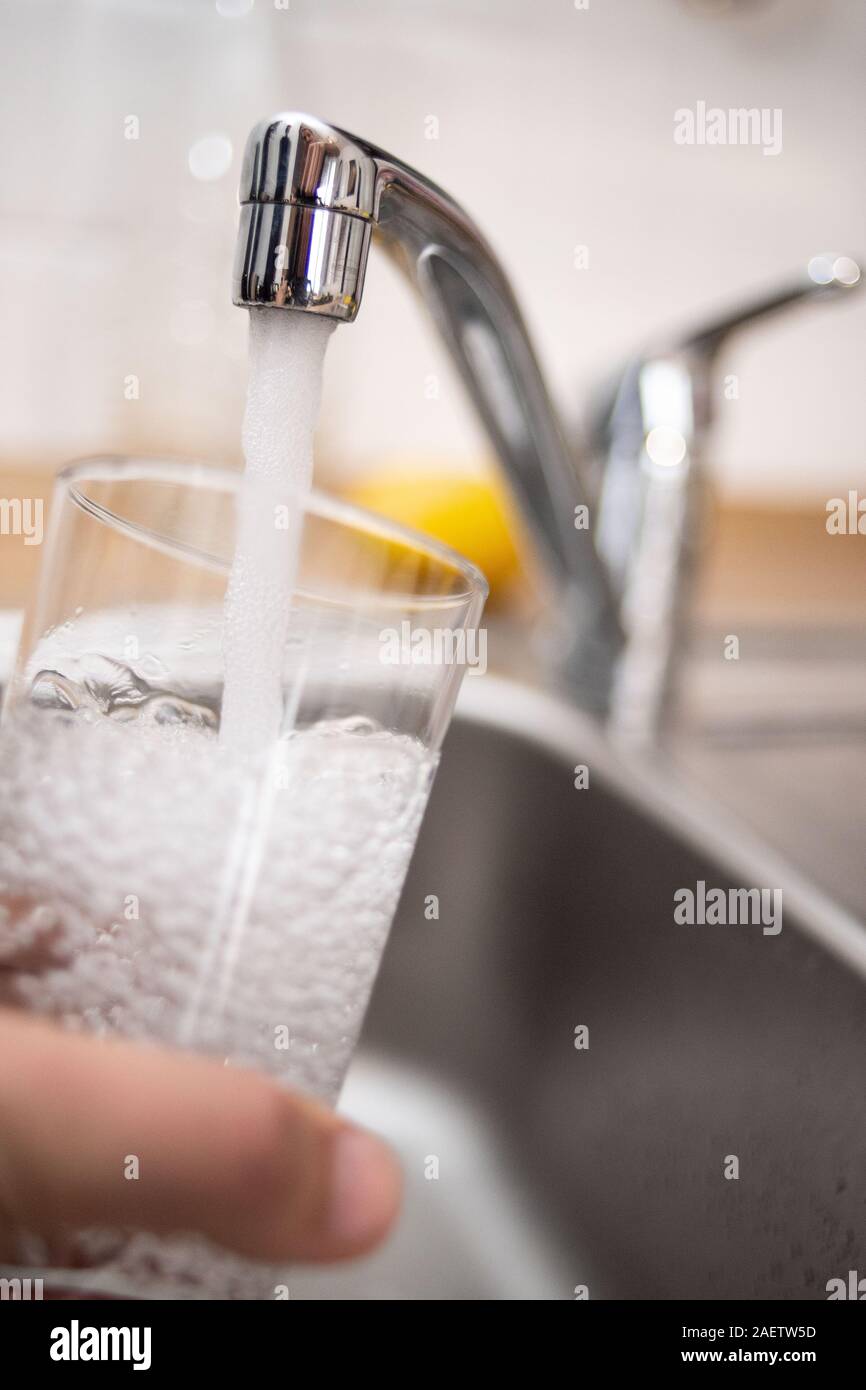 Düsseldorf, Deutschland. 10 Dez, 2019. Abbildung - ein Mann hält ein Glas unter fließendem Wasser. Bündnis 90/Die Grünen Gruppe Kommentare sterben auf den Ergebnissen einer großen Anfrage auf Wasser in NRW. Eine der Fragen, die auf dem Spiel steht, ist die Entwicklung des Haushalts der Wasserverbrauch. Credit: Marius Becker/dpa/Alamy leben Nachrichten Stockfoto