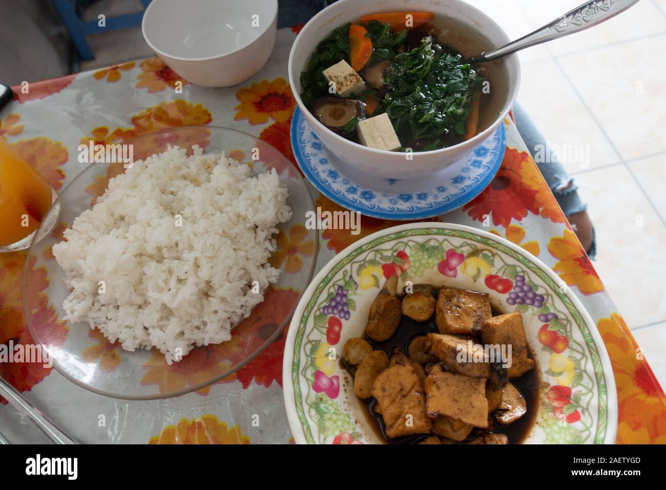 Eine Mahlzeit, bestehend aus Reis, in der Pfanne gebratener Tofu in Pilzsauce, und Gemüsesuppe serviert ein veganes Restaurant in Ho Chi Minh City, Vietnam Stockfoto