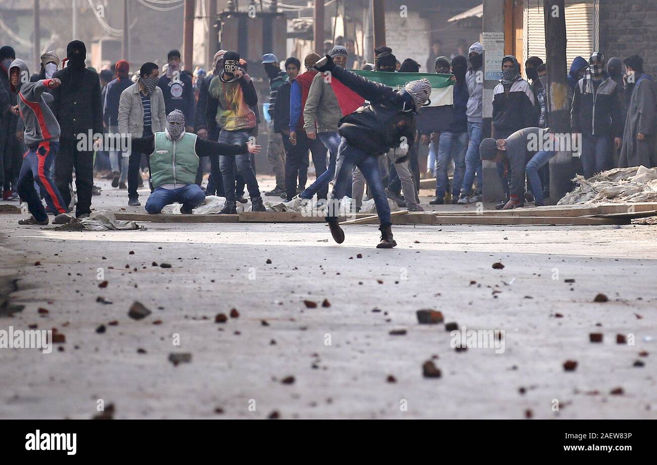 Ein Demonstrant in Kaschmir wirft einen Stein in Richtung indische Polizei während eines Protestes in Srinagar Stockfoto