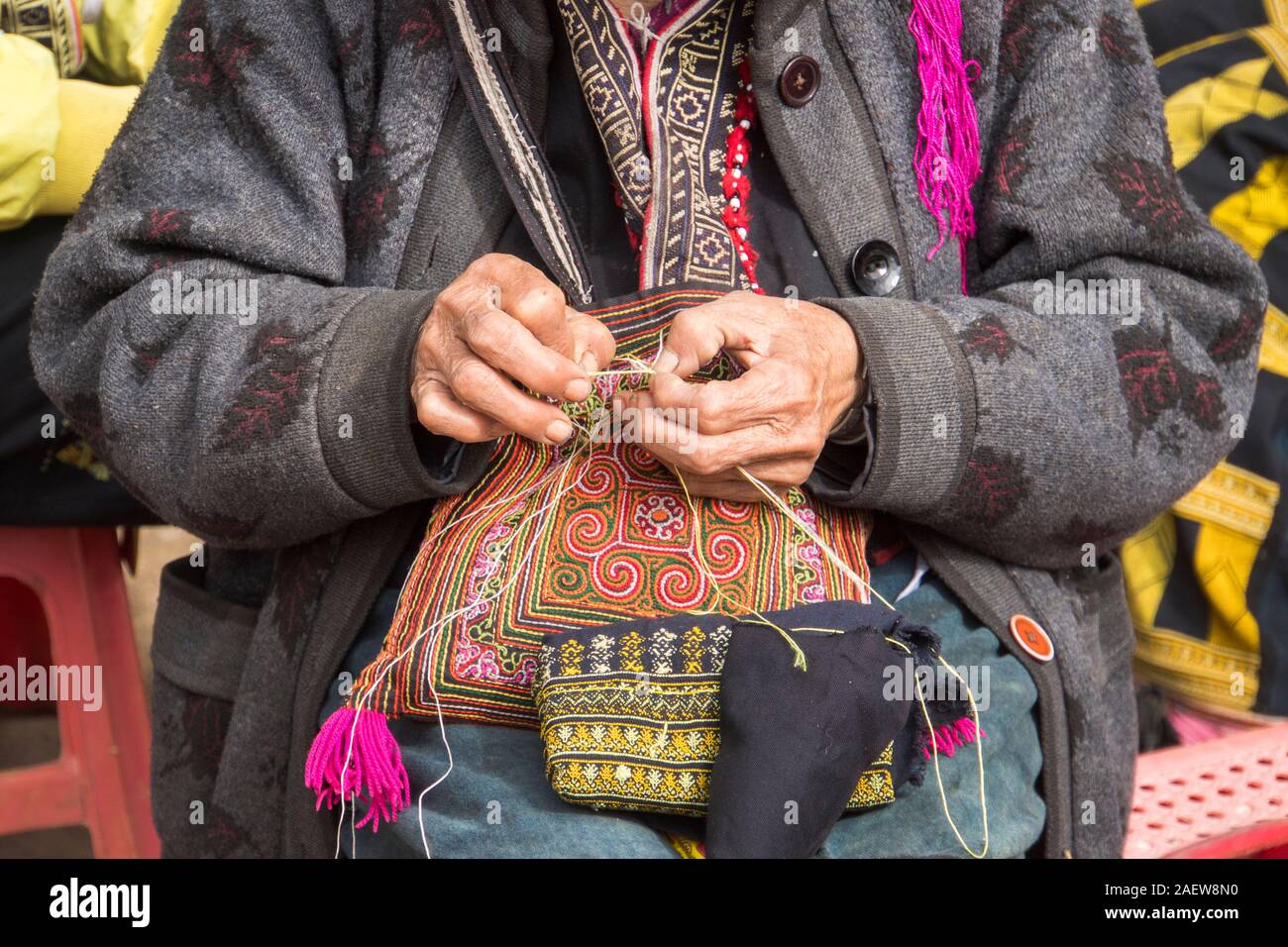 Roten Dzao ethnische Minderheit Frau nähen in Sa Pa, Lao Cai Provinz, Vietnam. Eine ältere Frau näht auf der Straße. Schöne Stickerei als souveni Stockfoto