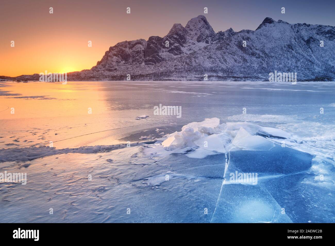 Eine gefrorene Fjord auf den Lofoten im Norden Norwegens mit der niedrigen Mittagssonne hinter den Bergen. Stockfoto