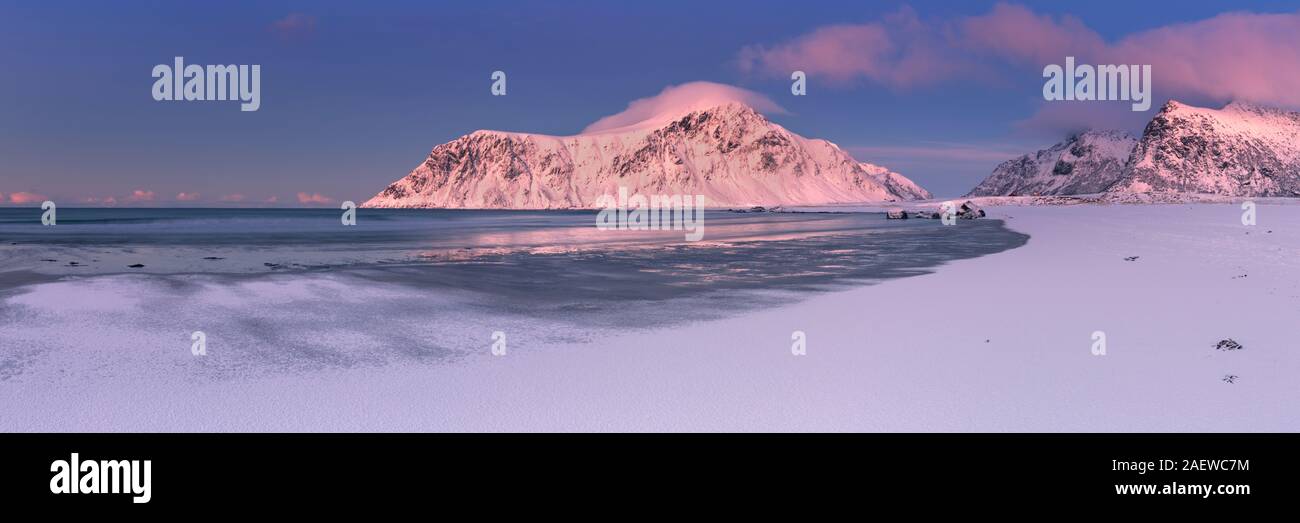 Alpenglühen am felsigen Strand von Skagsanden auf den Lofoten im Norden Norwegens, in der Dämmerung im Winter fotografiert. Stockfoto