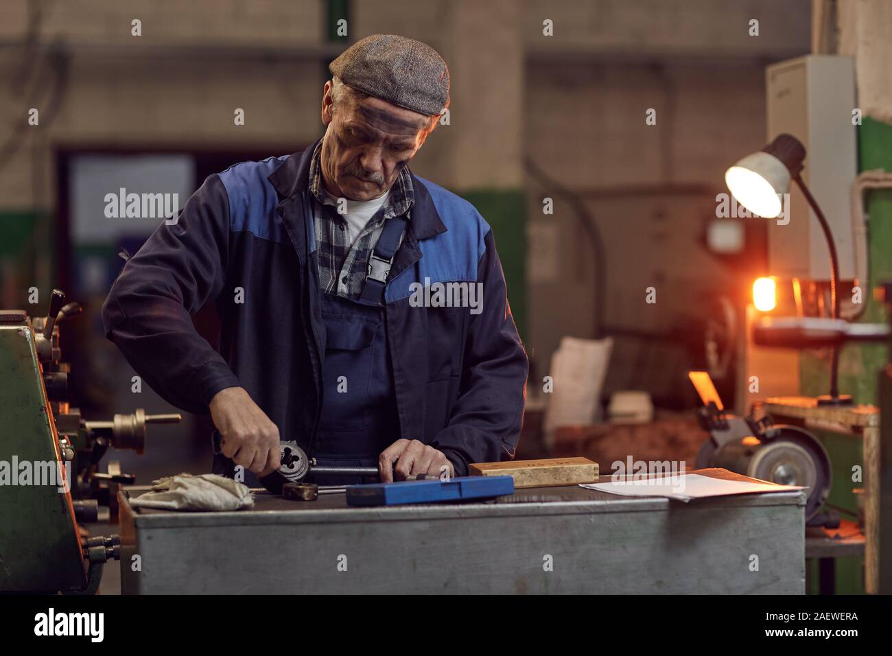 Ältere Arbeiter Instandsetzung Details an der Drehbank in der Anlage Stockfoto