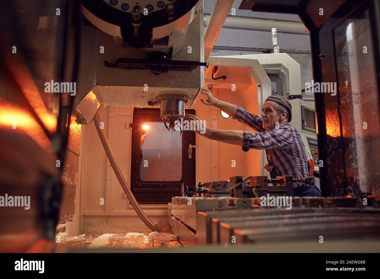 Ältere Fahrer in der Nähe der Maschine und der Kontrolle der Erzeugung von Details in der Factory Stockfoto