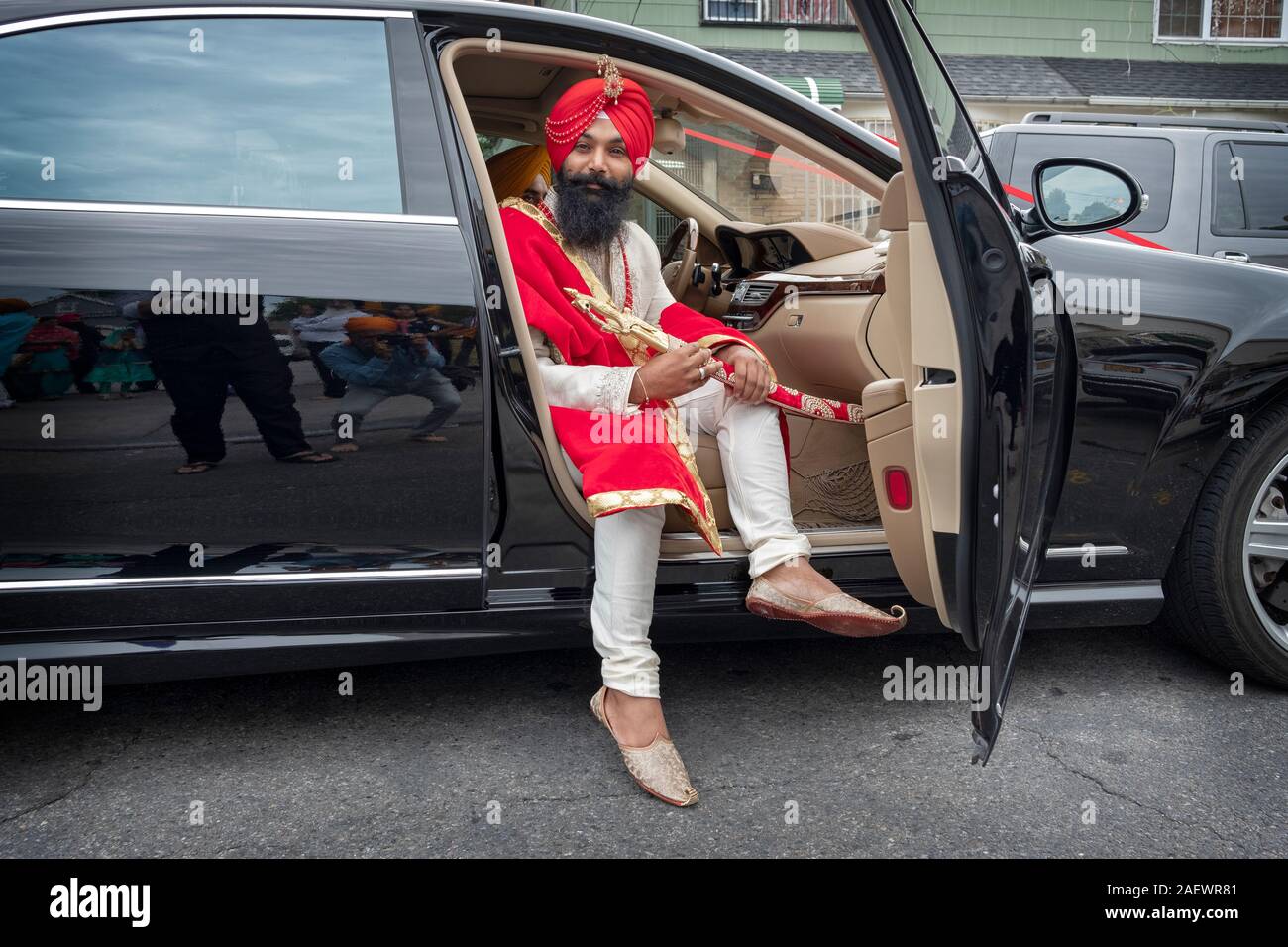 Ein Sikh Bräutigam in traditioneller Kleidung kommt in eine Limousine für die Hochzeit Zeremonie. In South Richmond Hill, Queens, New York. Stockfoto