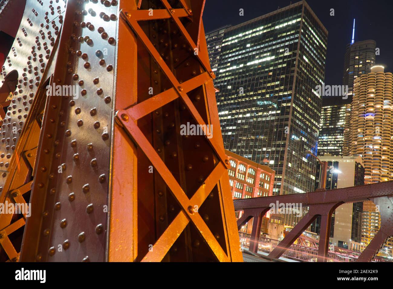 Nacht detail Aufnahme der Brücke überführung Stahlstützen mit städtischen Skyline der Stadt beleuchtet im Hintergrund Stockfoto