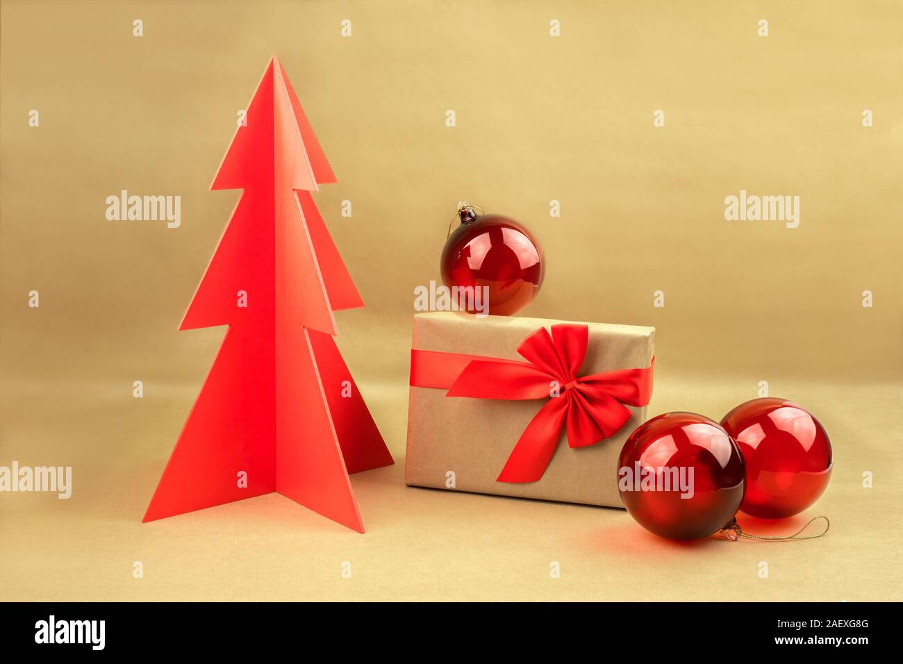 Geschenkbox mit Schleife und rote Kugeln mit Woodden Weihnachtsbaum auf einem natürlichen braunen Hintergrund. Stockfoto