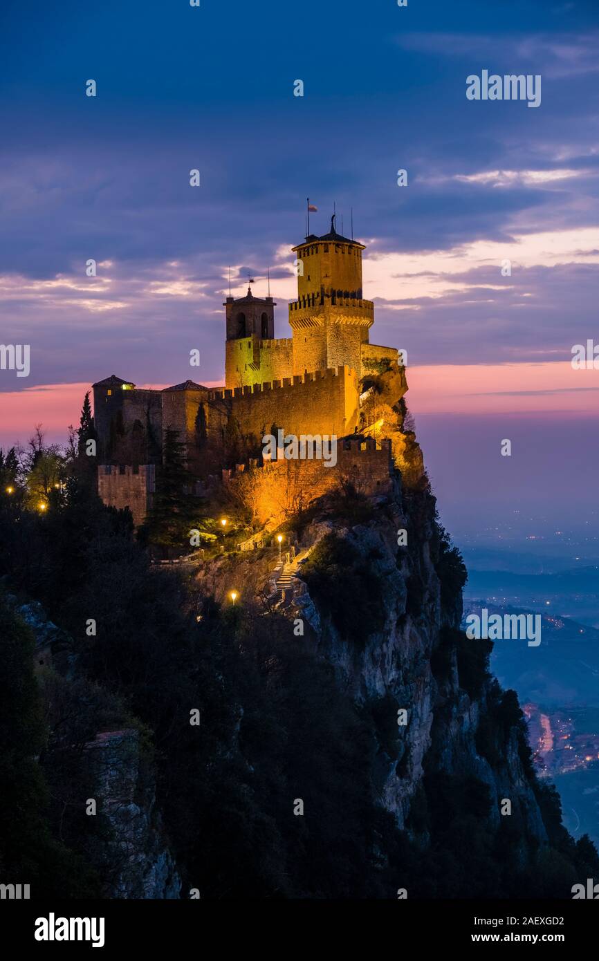 Blick auf das beleuchtete Guaita Festung auf dem Monte Titano, bergige Landschaft in der Ferne, in der Nacht Stockfoto