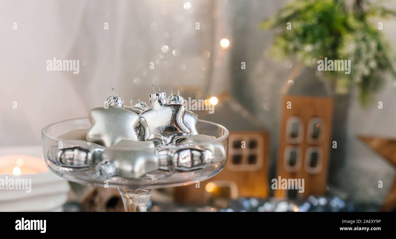 Glas Silber Sterne in einem Glas Vase. Weihnachtsbaum Spielzeug in einem Glas auf einem Hintergrund von glänzenden Stoff und Tannenzapfen. Kopieren Sie Platz. Stockfoto