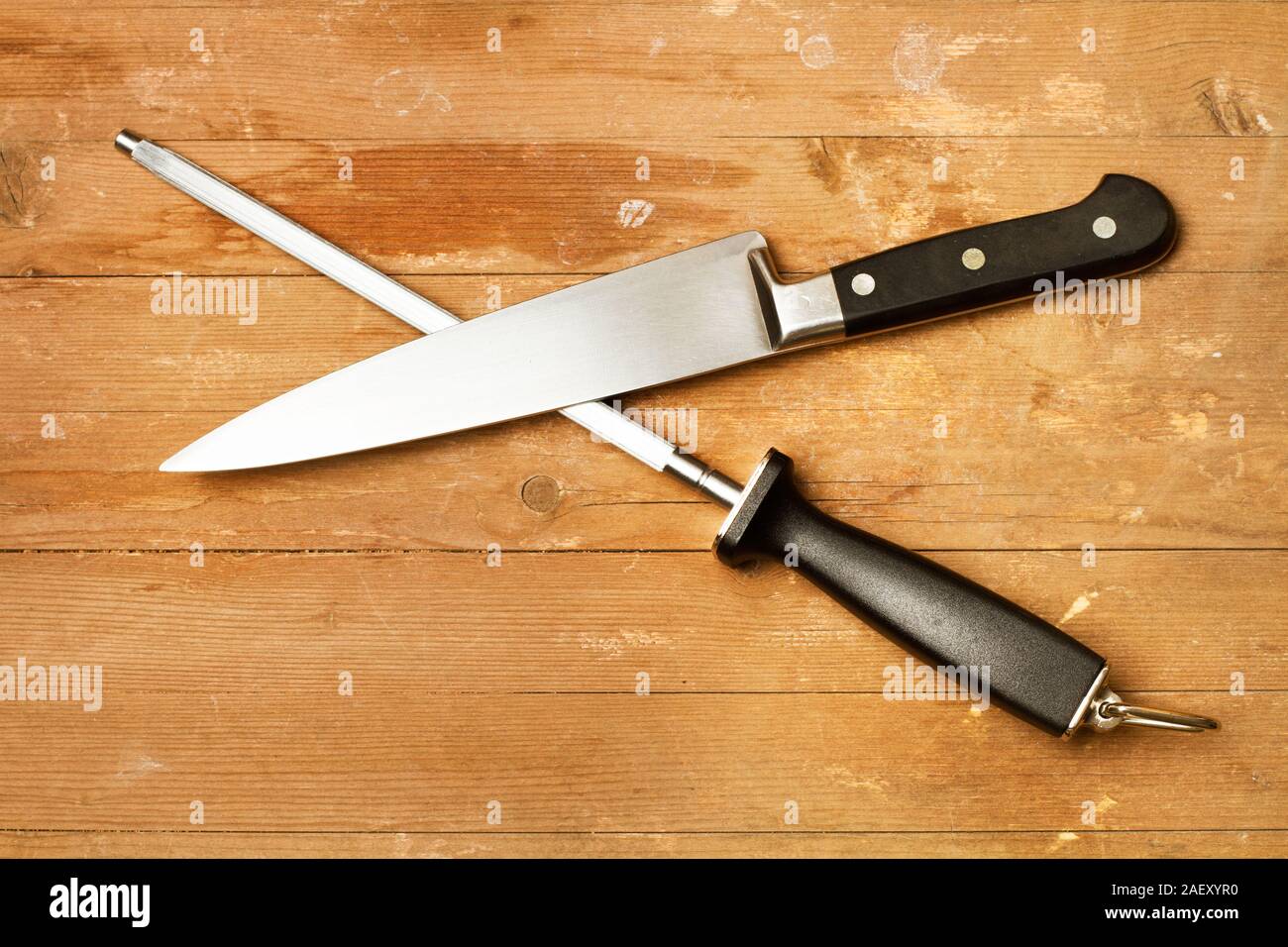 Stahl spitzer und eine Küche Messer auf einem rustikalen Holztisch in einer Ansicht von oben Stockfoto