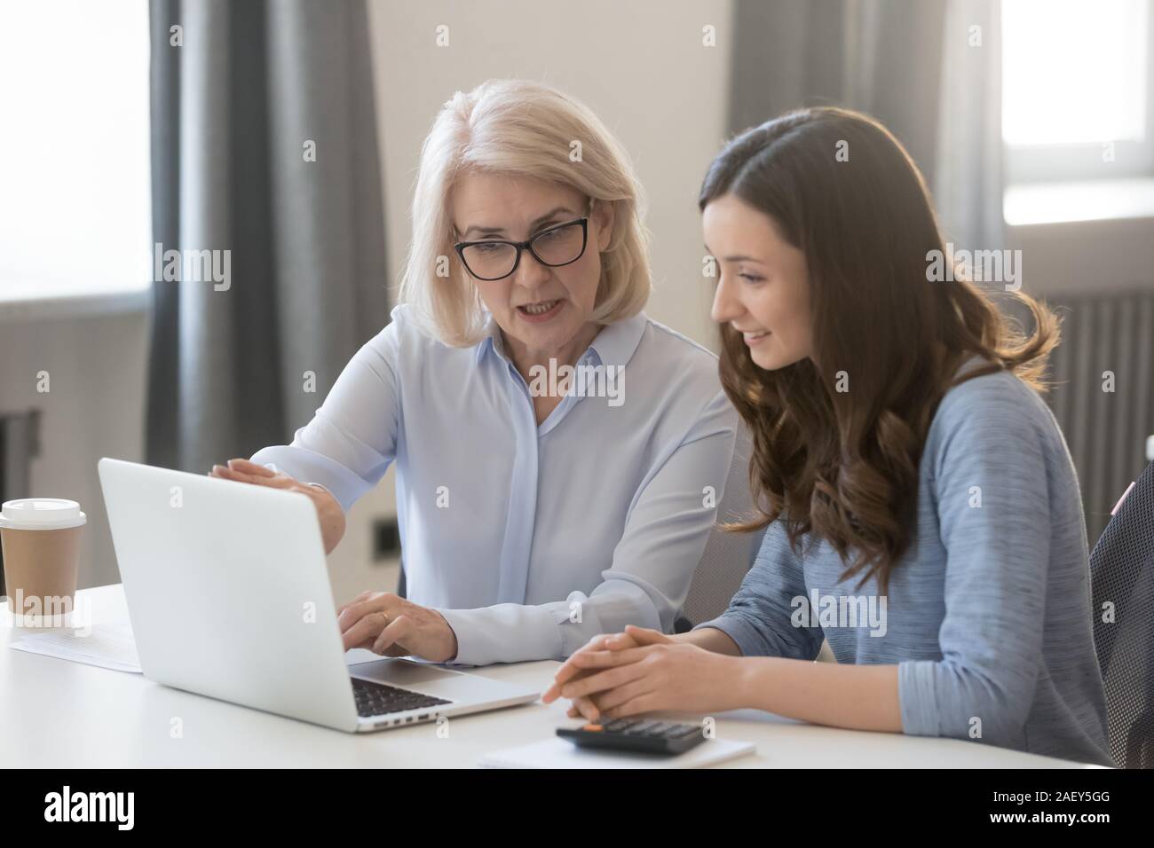 Im mittleren Alter Geschäftsfrau zug Young Business Kollege am Laptop Stockfoto