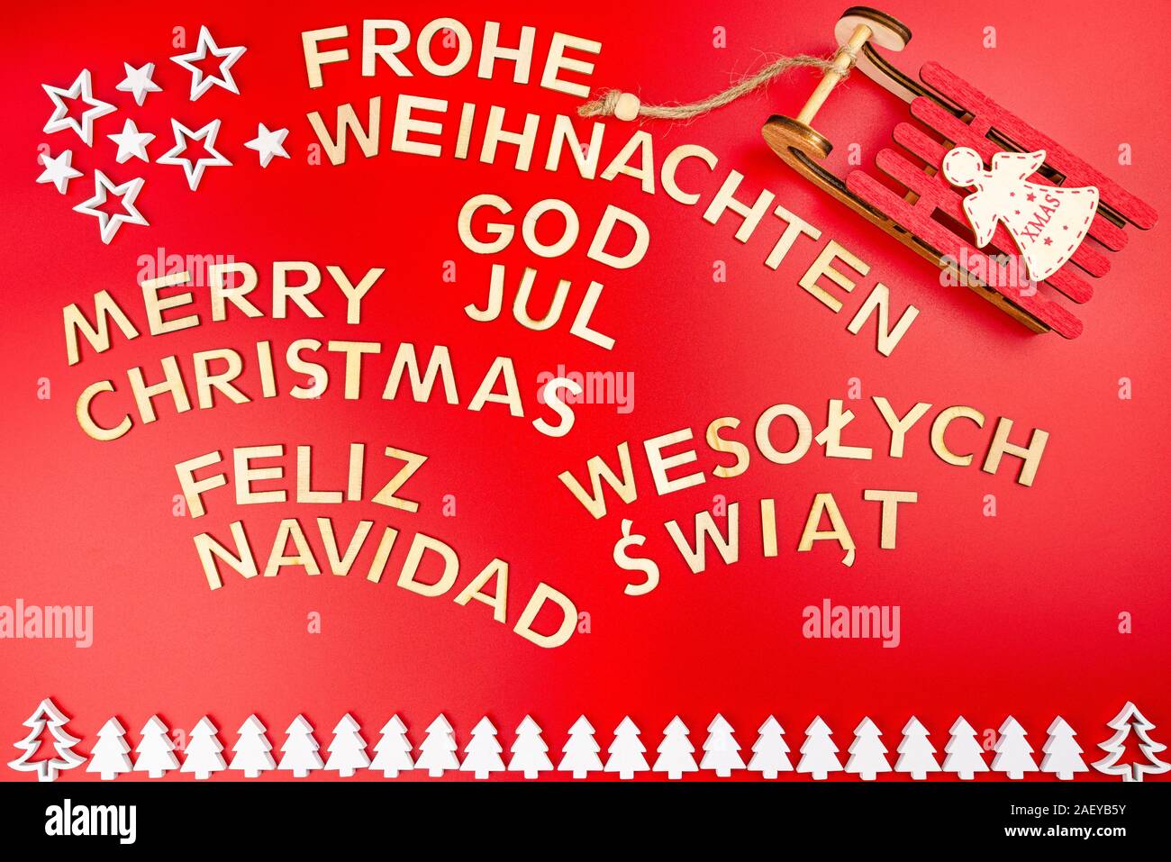 Aufschrift Frohe Weihnachten in Deutsch, Englisch, Polnisch, Schwedisch und  Spanisch, liegend von oben. Von Holz- Inschriften, auf einem roten Bac  isoliert Stockfotografie - Alamy