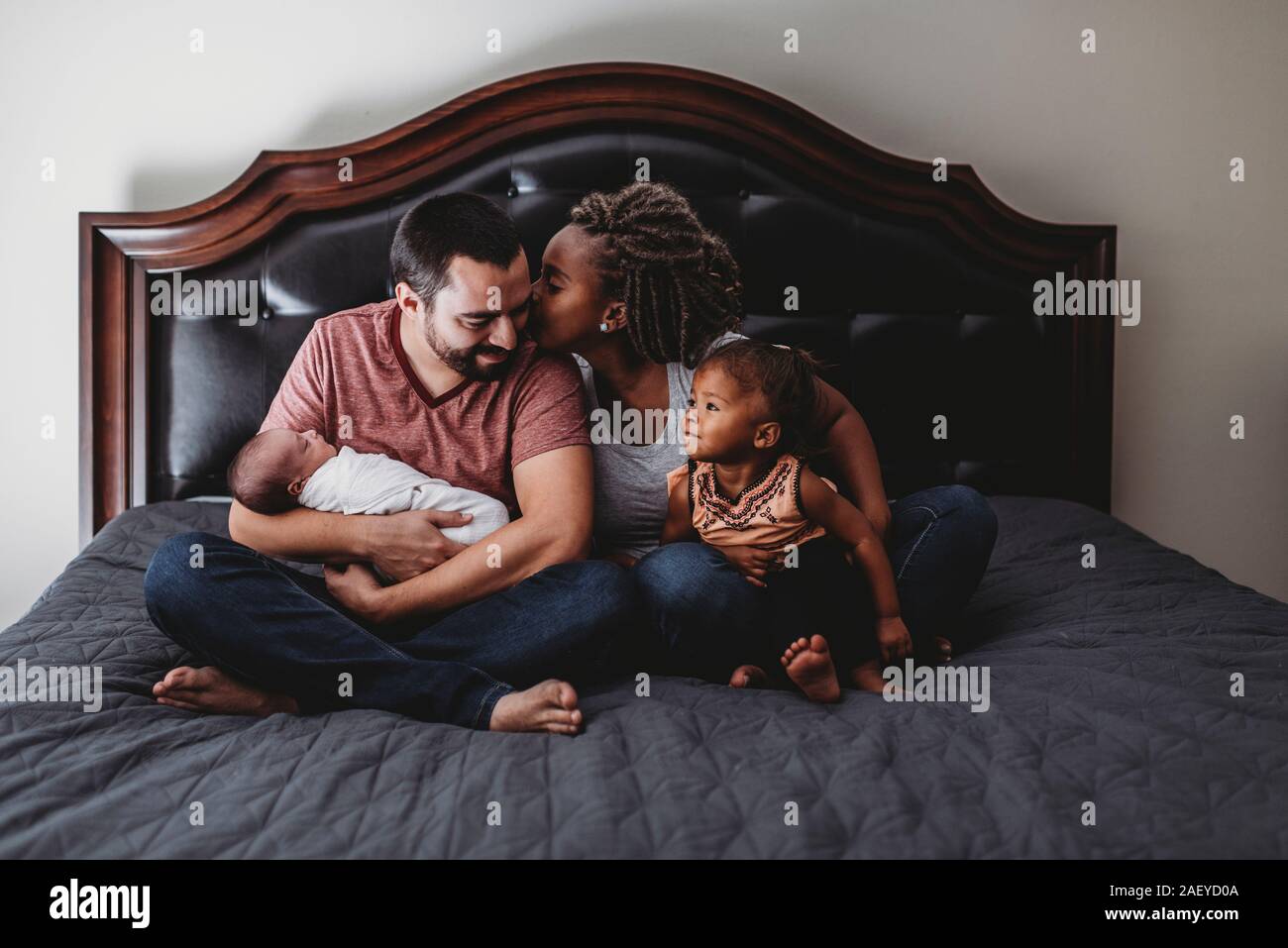 Ethnische Frau küssen Mann sitzen auf dem Bett mit Multirassischen Kinder Stockfoto