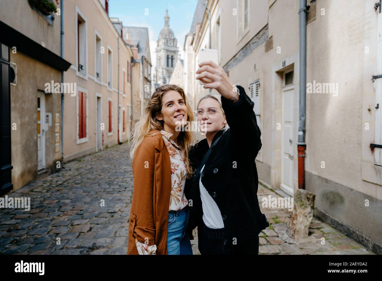 Junge Frauen, die selfie in einer typischen französischen Stadt Straße Stockfoto