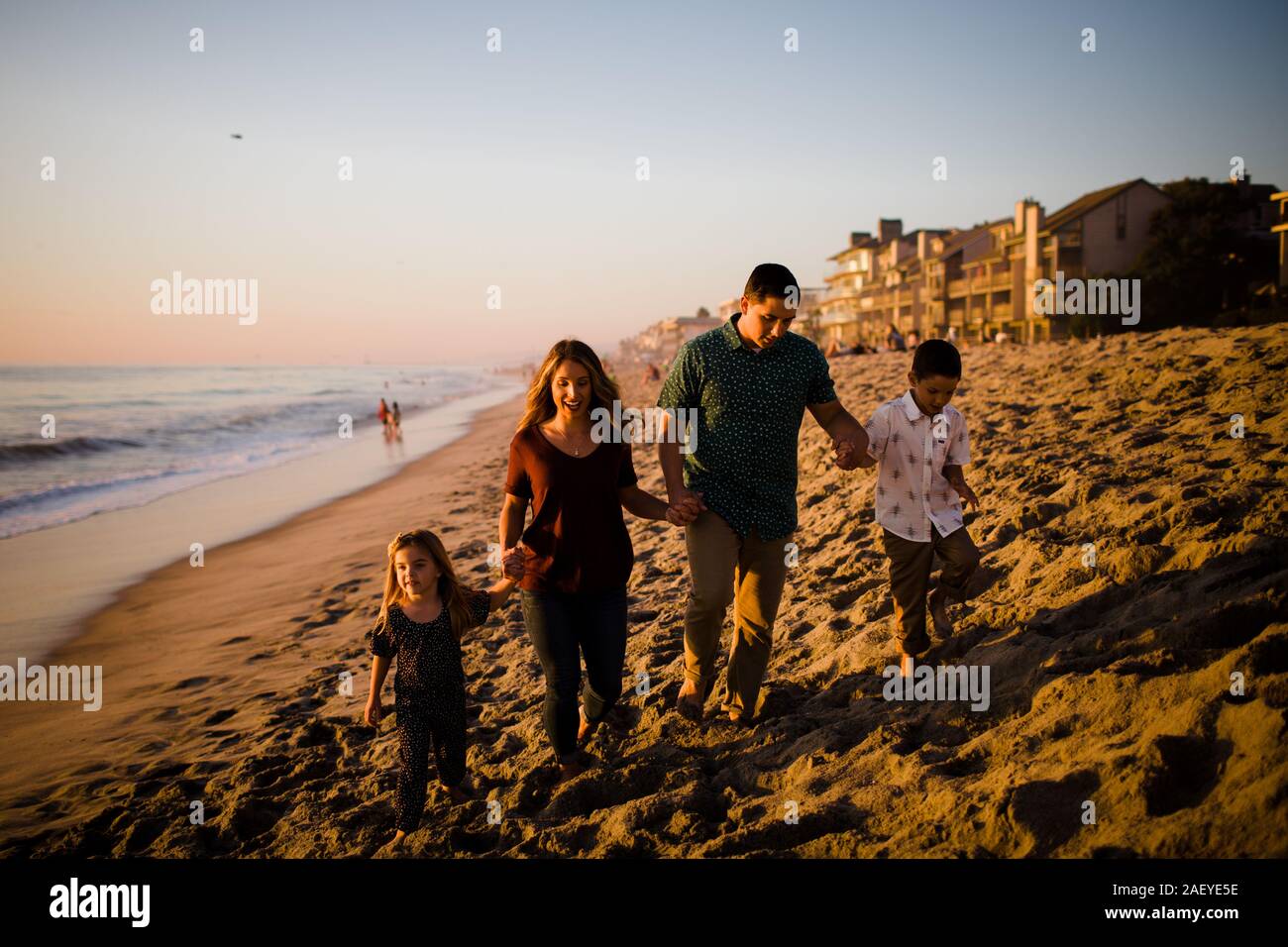 Familie von vier Hände halten, Wandern am Strand bei Sonnenuntergang Stockfoto