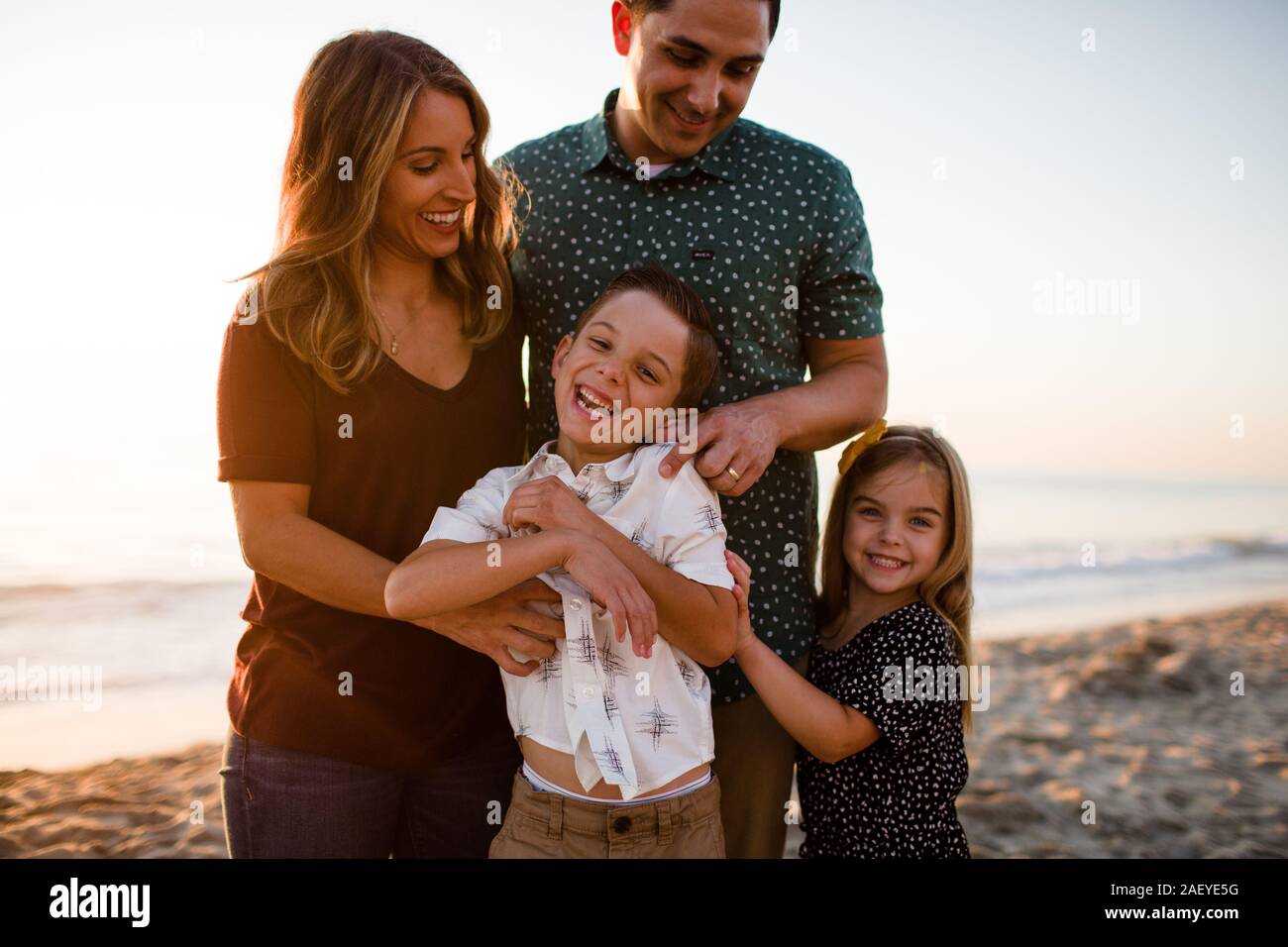 Familie von vier Spielen & Lächeln am Strand bei Sonnenuntergang Stockfoto