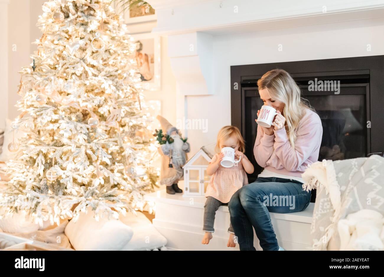Mutter und Baby das Trinken aus Becher durch Weihnachtsbaum Stockfoto