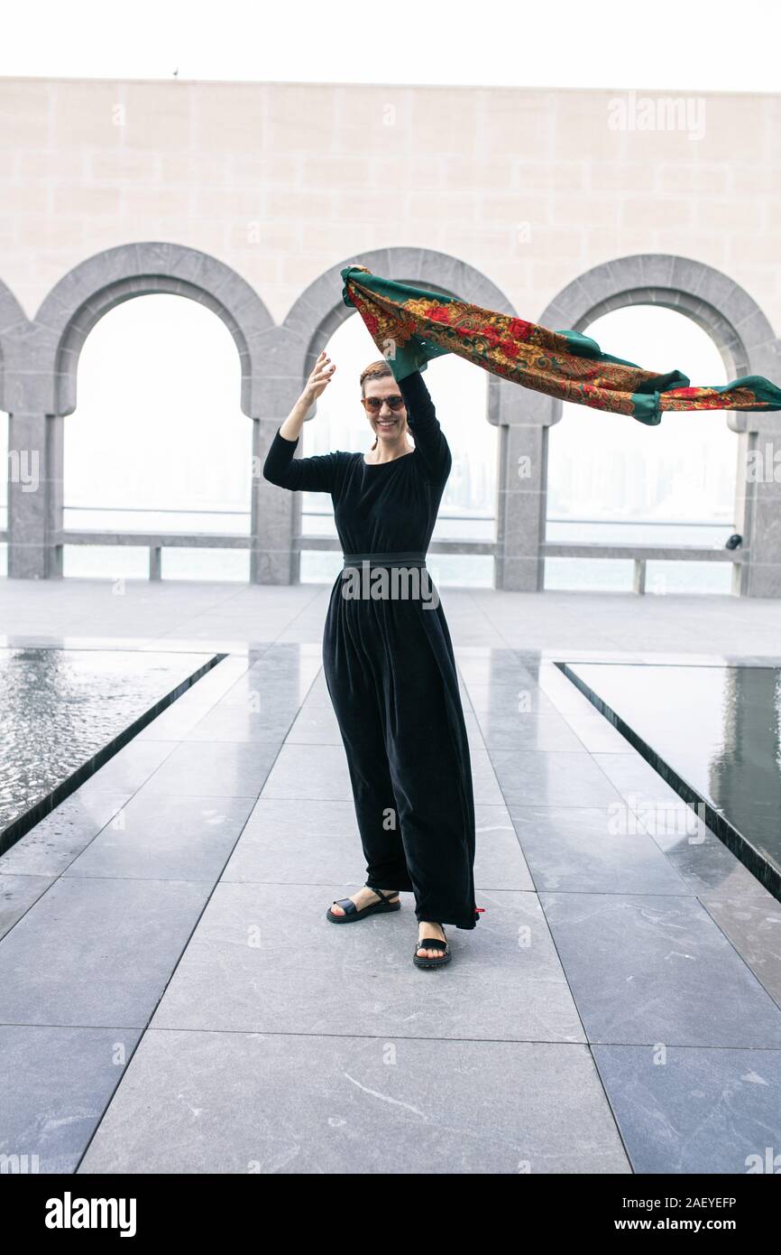 Junge Frau stehen und ihre bunten Schal Holding auf Wind Stockfoto