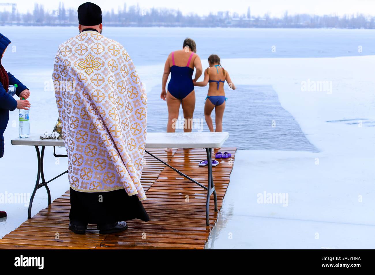Die Menschen Baden im Fluss während der Orthodoxen Dreikönigstag, ein Priester in der Kirche Kleidung ein Gebet liest und heiligt das Wasser. Winter Sport, Schwimmen, t Stockfoto