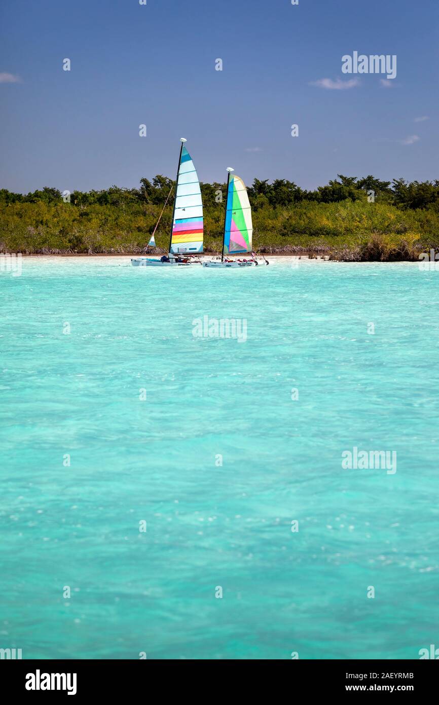 Ein paar Segelboote im azurblauen Wasser des „Sees of Seven Blues“ in Bacalar, Quintana Roo, Mexiko. Stockfoto