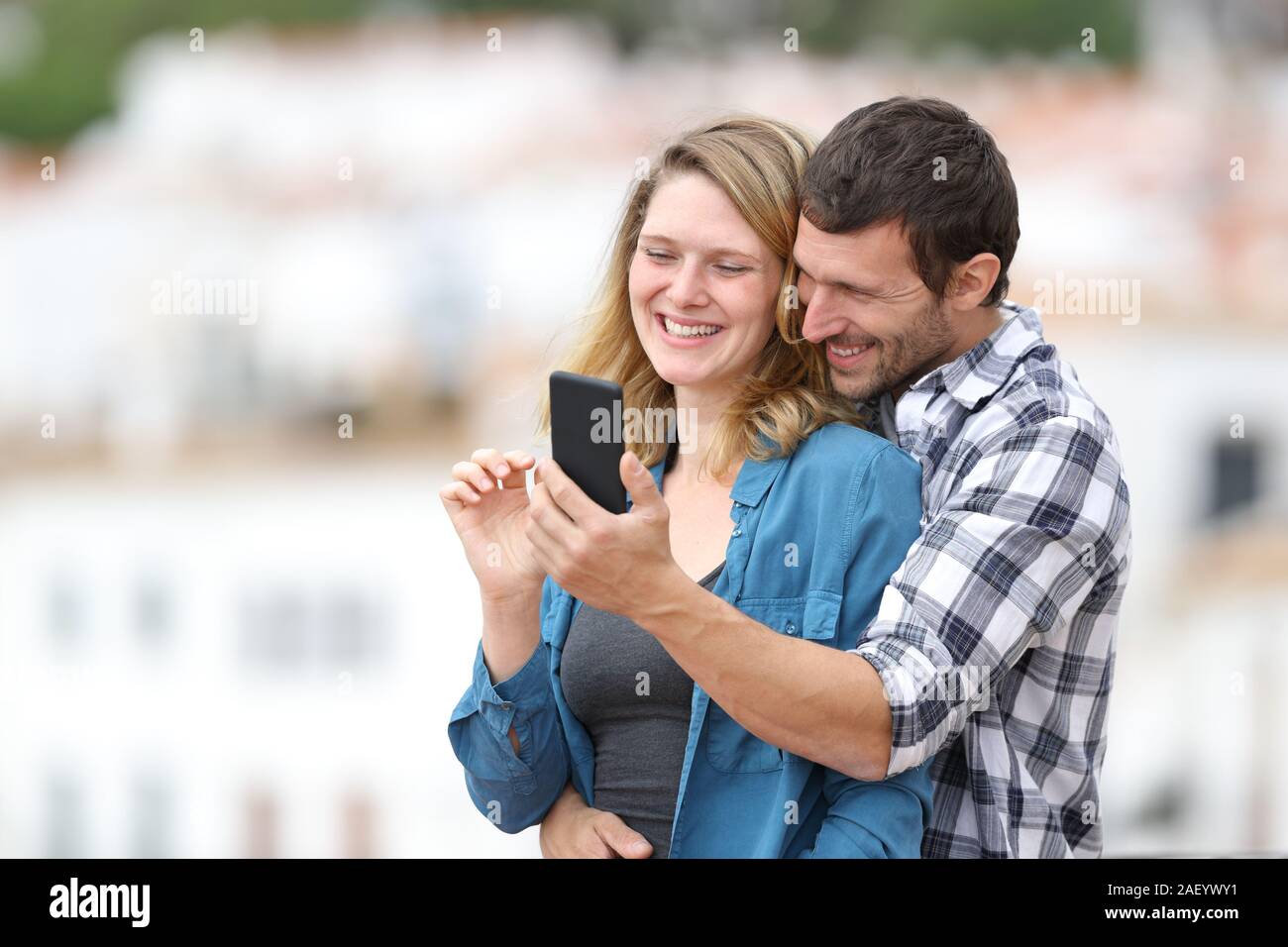 Glückliches Paar in der Liebe Kontrolle Mobiltelefon stehen draußen in einen Balkon in einer ländlichen Stadt Stockfoto