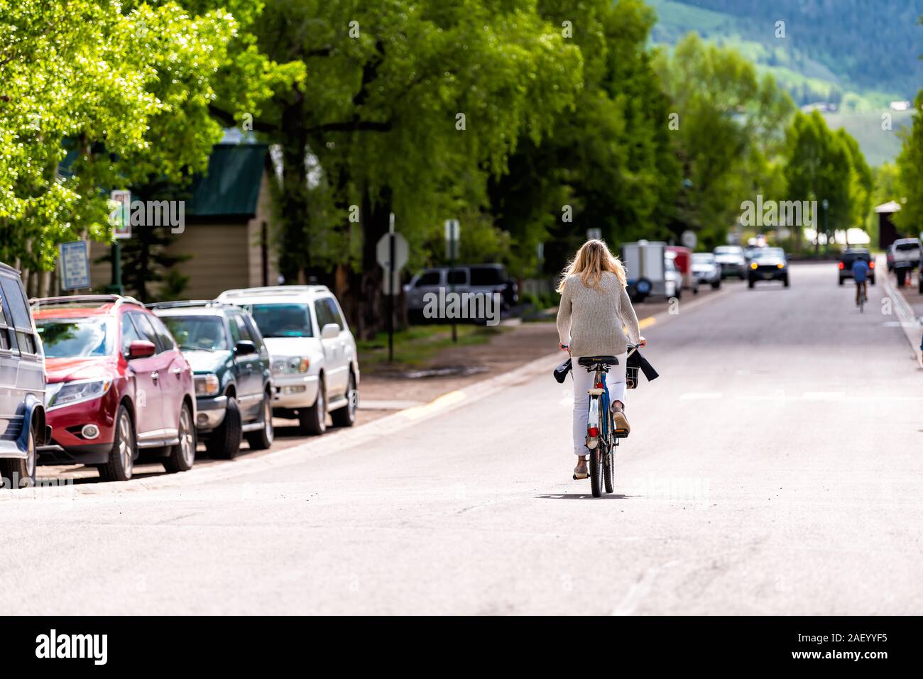 Crested Butte, USA - Juni 21, 2019: Colorado Dorf Kleinstadt Wohngegend im Sommer mit Frau Reiten Fahrrad auf der Straße Stockfoto