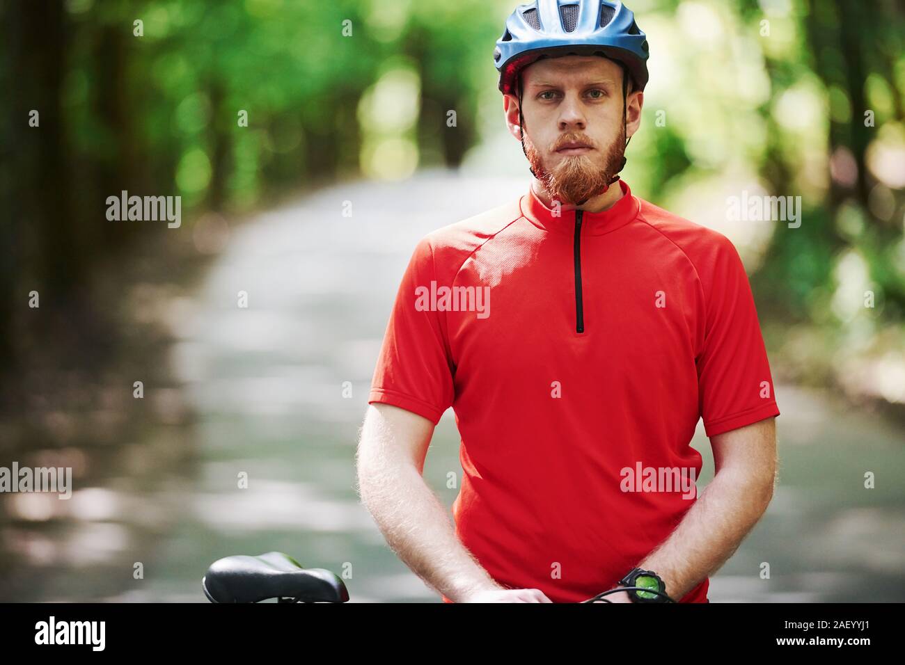 Bereit und vorbereitet. Radfahrer mit dem Rad auf der asphaltierten Straße im Wald an einem sonnigen Tag Stockfoto