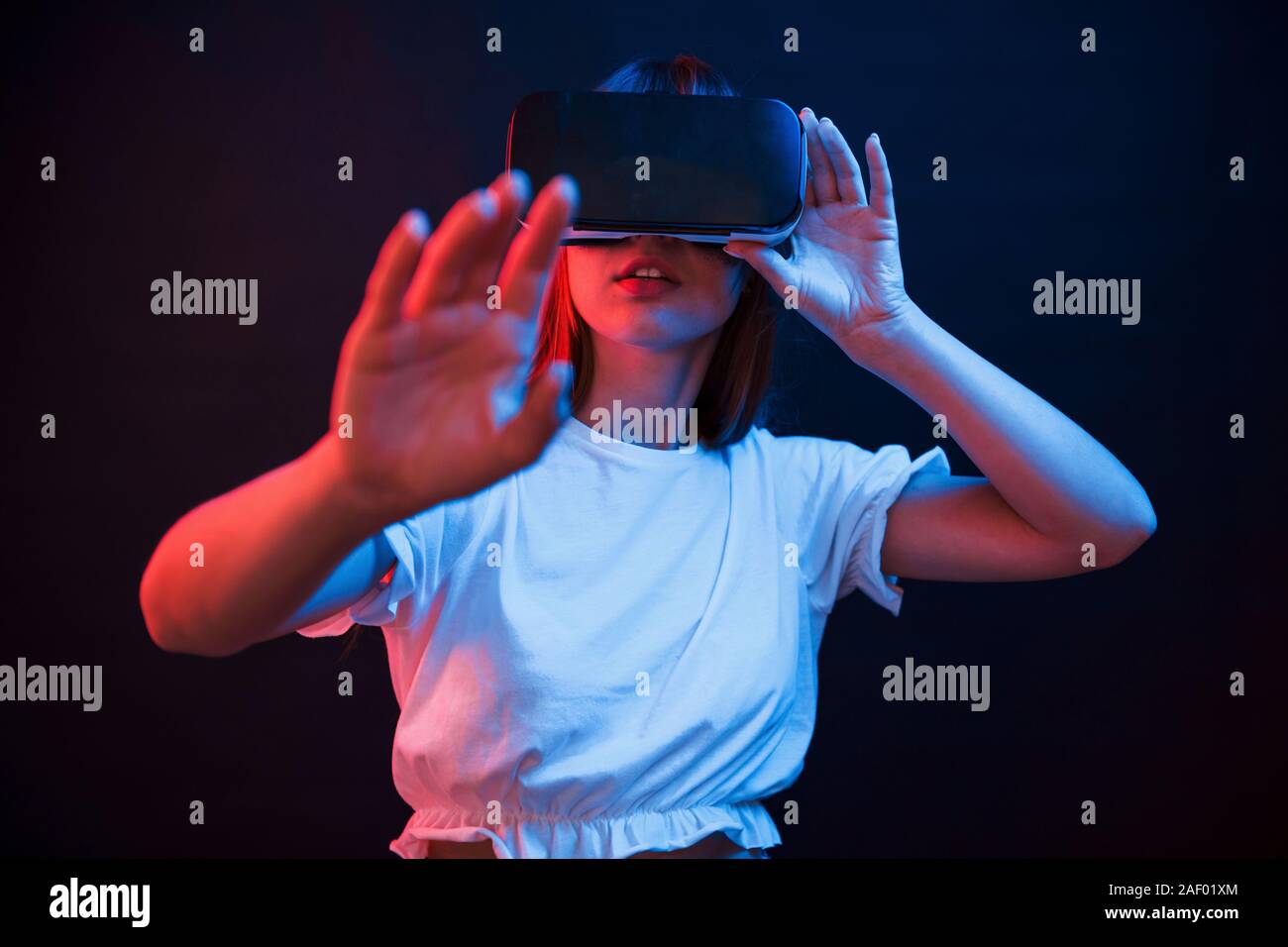 Drahtlose Technologien. Junge Frau mit Virtual reality Brillen im dunklen Zimmer mit Neon Beleuchtung Stockfoto