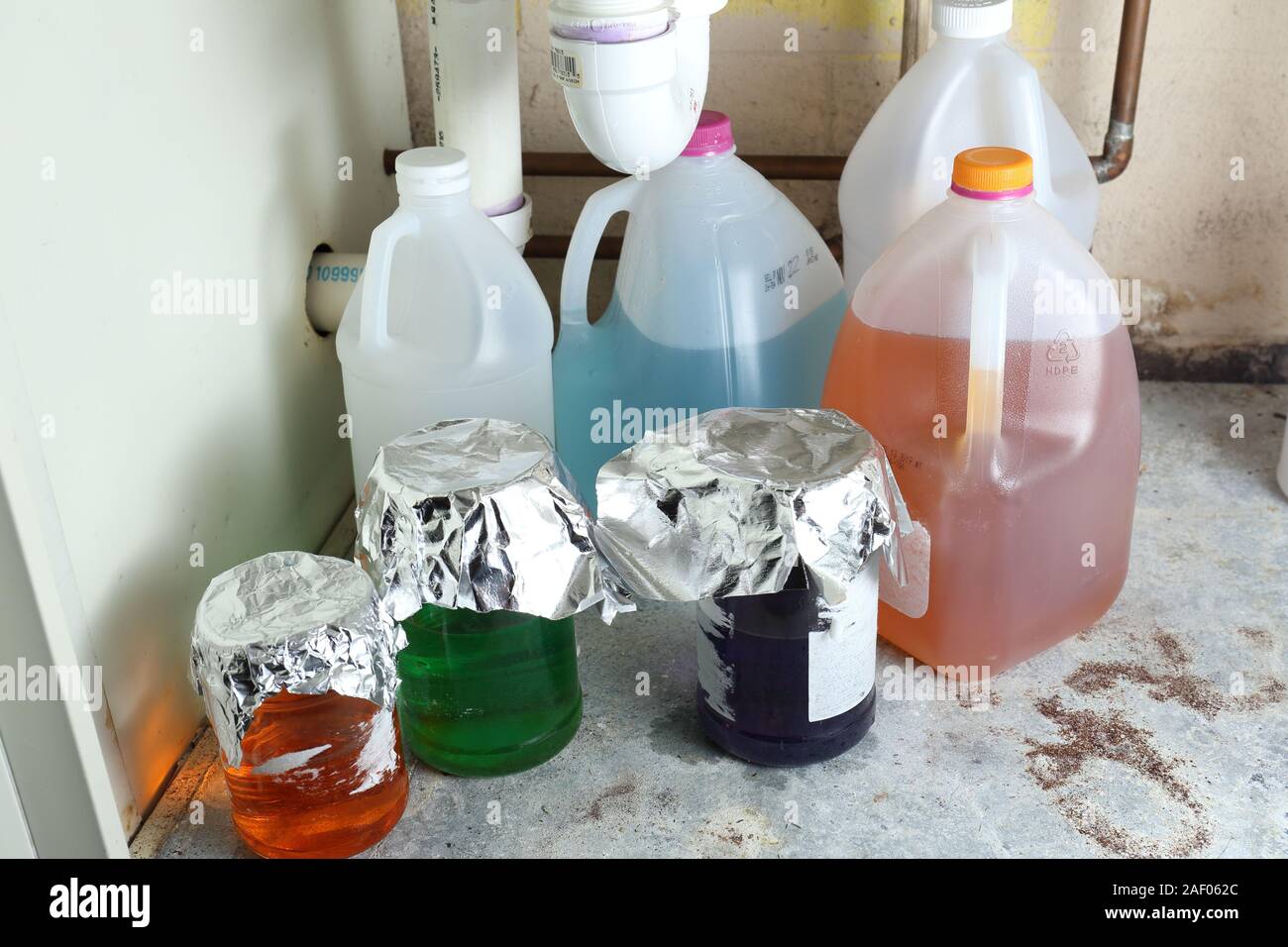 Vielfalt in den geheimnisvollen Chemikalien unsachgemäß gelagert und unbeschriftet in Kannen und Gläser unter einem Waschbecken Stockfoto