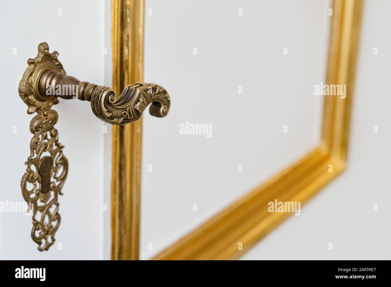 Seite Detail anzeigen Vintage antiken goldenen Türknopf mit metallischen Schnitzereien und Schlüsselloch auf weißem Eingang natürliche Blitz Stockfoto