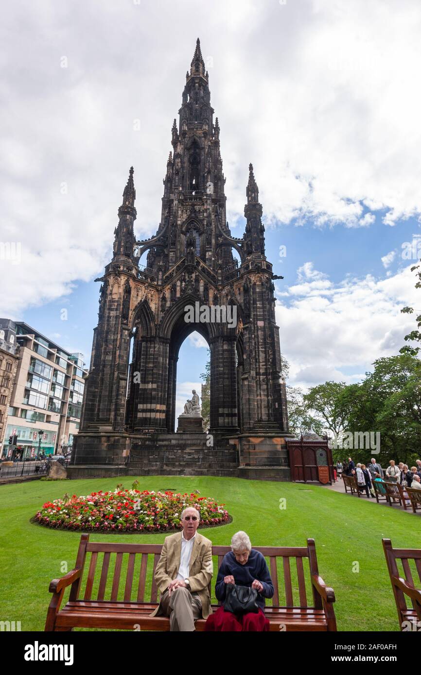 Alte Paar in einer Bank in der Nähe von Scott Monument, einem viktorianischen gotische Denkmal, Princes Street, Edinburgh, Schottland, UK sitzt Stockfoto