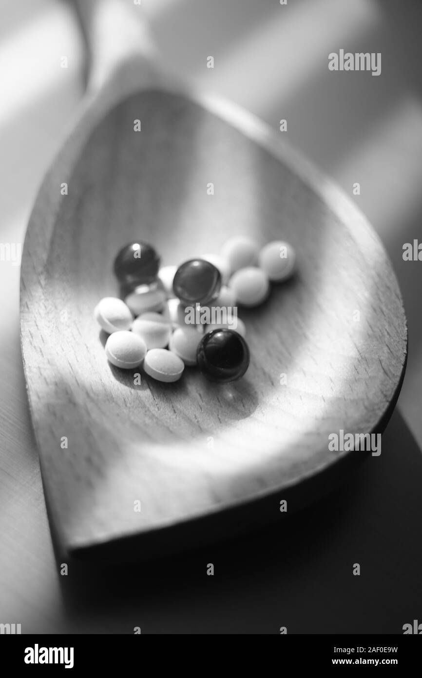 Medizinische Pillen und Vitaminen einem holzlöffel Nahaufnahme. Schwarz-weiß Foto. Stockfoto
