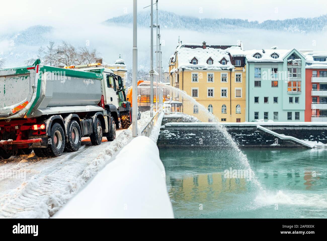 Schwere kommunale Dienstleistungen Maschinen Schnee entfernen aus den Straßen der Stadt. Großer Traktor Schneegebläse bläst den Schnee von Bridge Road in Fluss. Reinigung Straßen Stockfoto