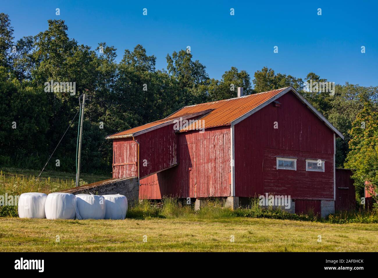 BAKKEJORD, INSEL KVALØYA, Troms, Norwegen - Rote Scheune und runde Heuballen. Stockfoto