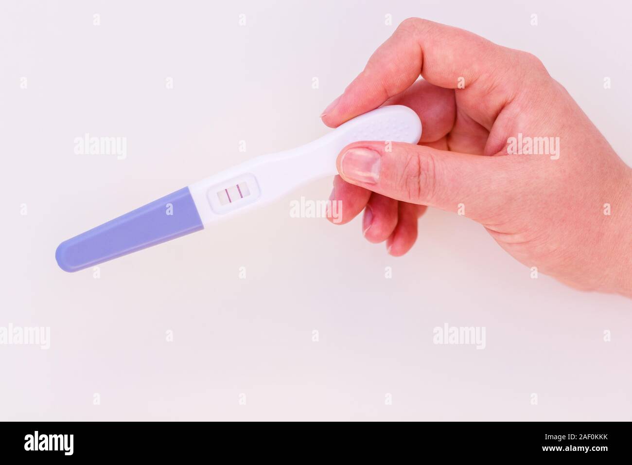 Schwangerschaft Test in weiblicher Hand zeigt ein positives Ergebnis isolieren auf weißem Hintergrund. Stockfoto