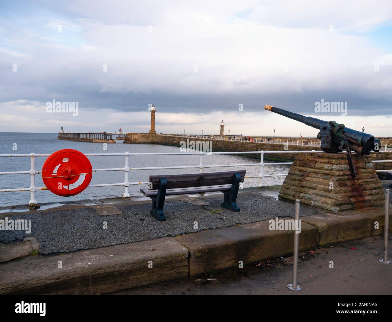 Eine Ansicht von Whitby West Pier von der Batterie Parade unter dem West Cliff mit einem alten Gewehr in Position Stockfoto